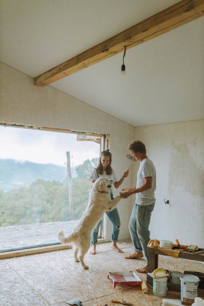 man, woman and dog in an unfinished room with paint supplies