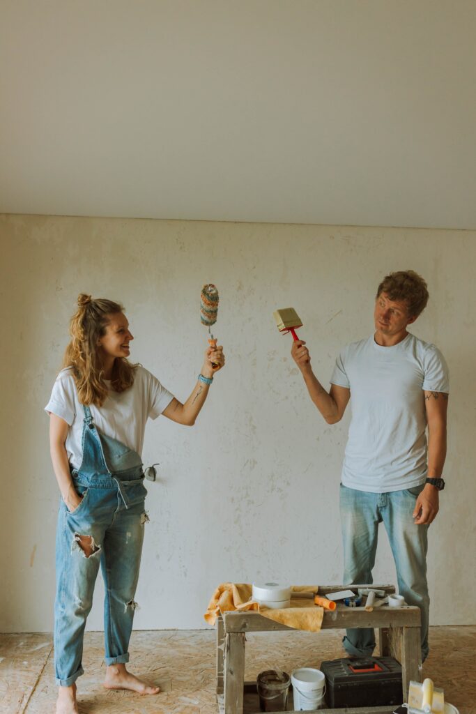 man and woman with paint rollers giving each other high five